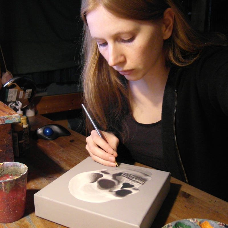 Kim Onyskiw painting a skull on a canvas